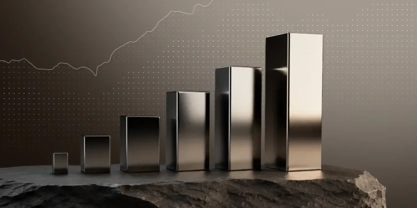 Row of polished metal blocks rising in height like a bar chart, standing on dark rock in front of an upward-trending line graph