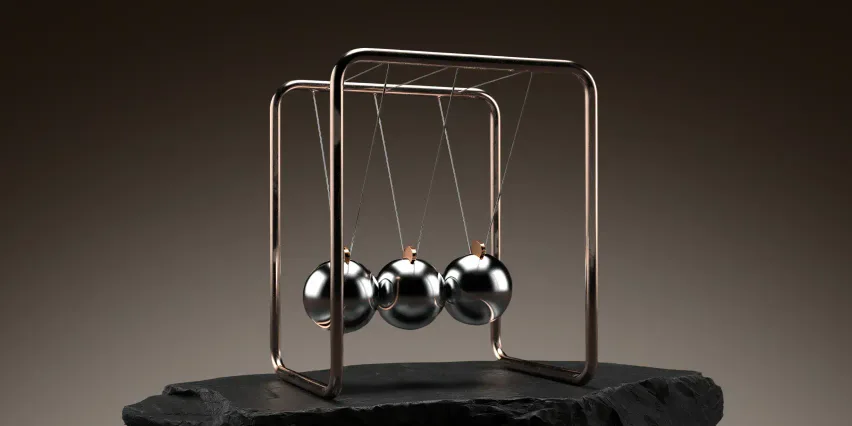 Chrome Newton's cradle with three polished steel balls hanging from a copper frame on a black slate slab, dark background.