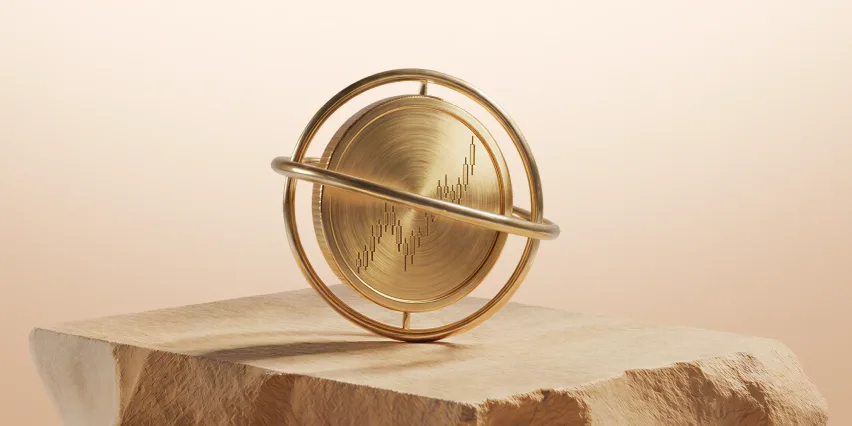 Brushed gold disc engraved with a candlestick chart, mounted in a gold gimbal ring on a block of desert sandstone