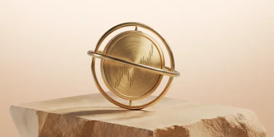 Brushed gold disc engraved with a candlestick chart, mounted in a gold gimbal ring on a block of desert sandstone